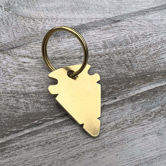 Gold colour dog tag with a unique design on a wooden surface