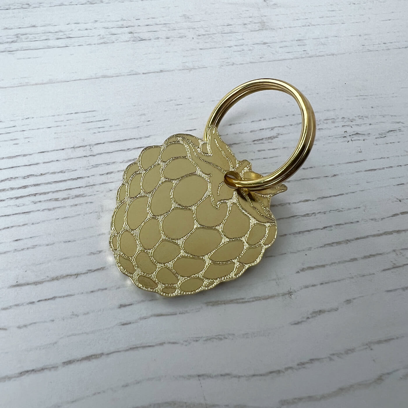 Gold textured keychain on a light wooden surface