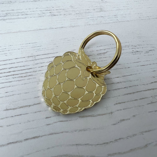 Gold textured keychain on a light wooden surface