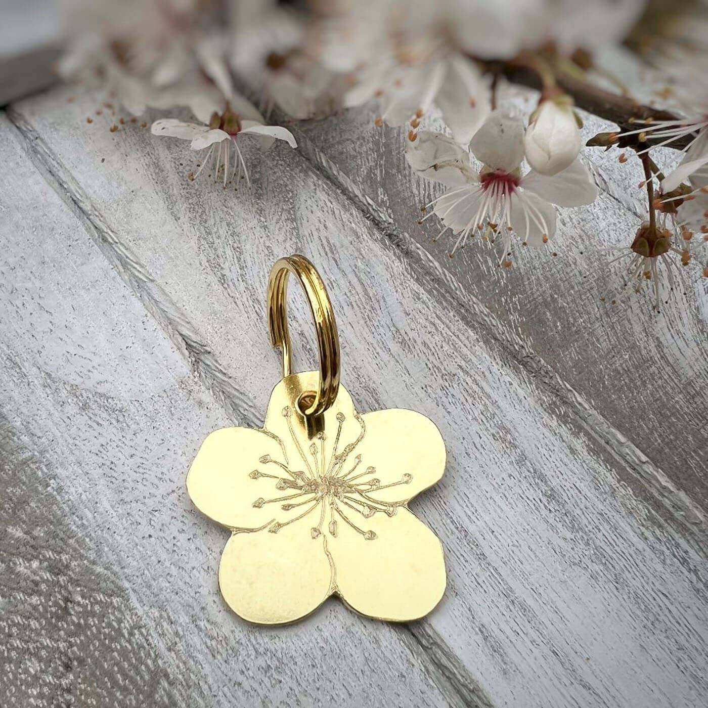 Gold flower tag on a wooden surface with cherry blossoms in the background