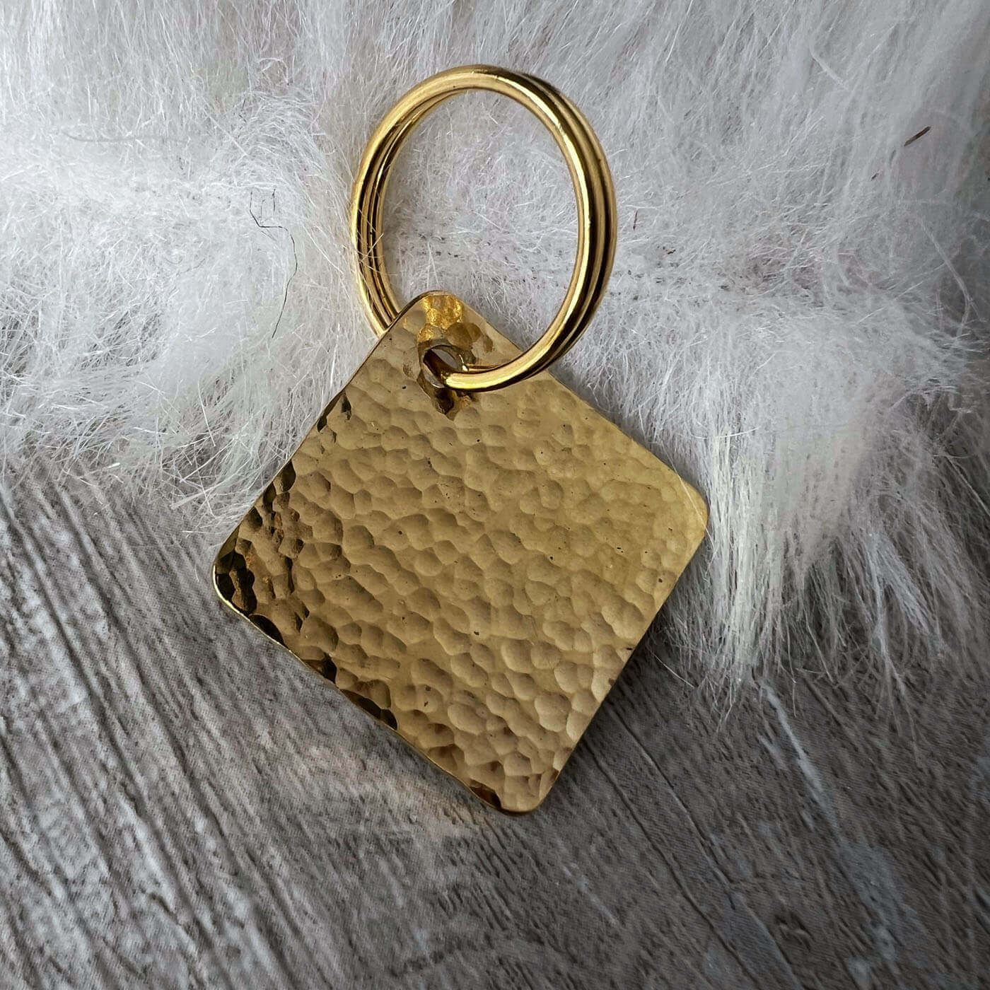 Gold textured square tag on a wooden surface with white fur background
