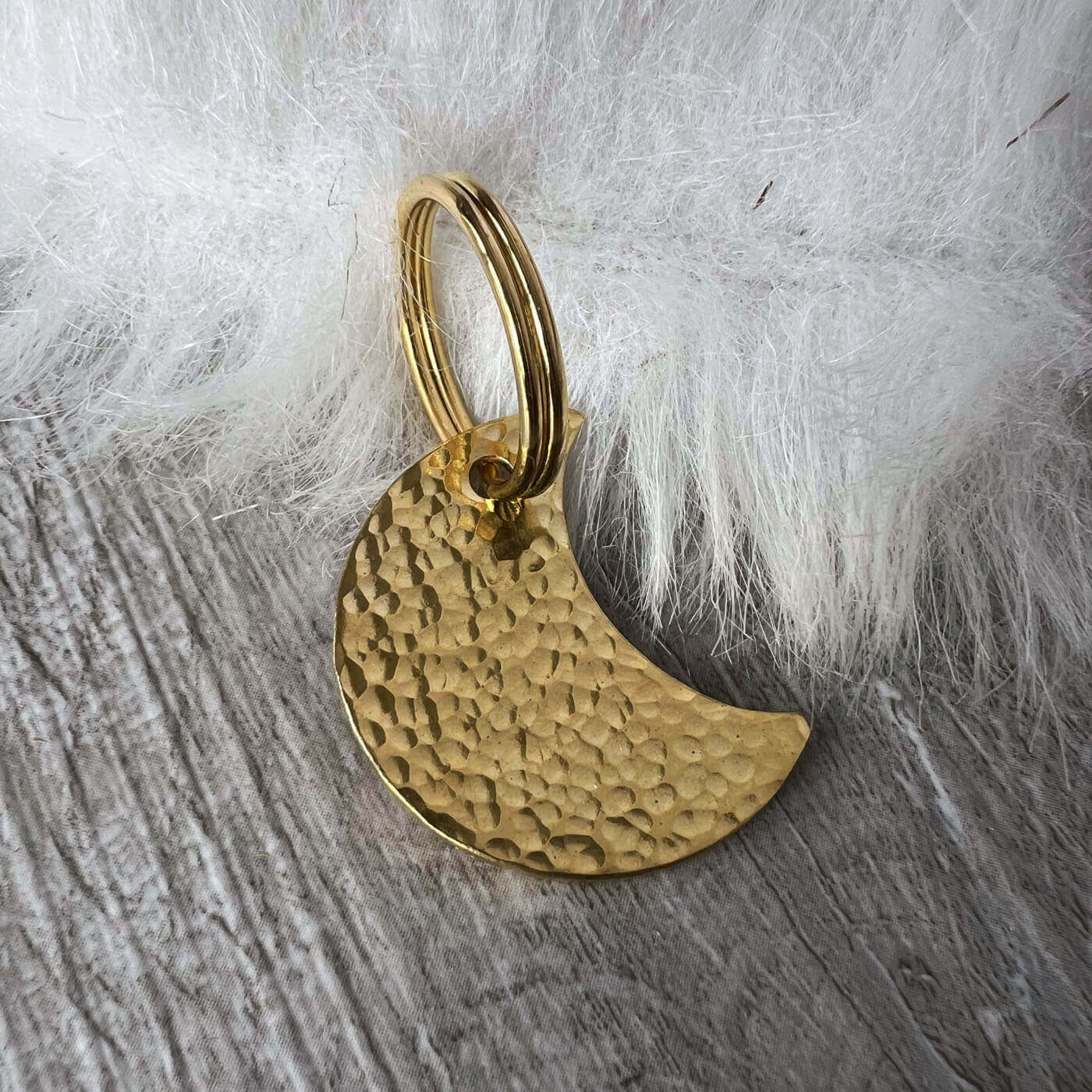 Gold colour crescent moon pendant on a textured gray surface