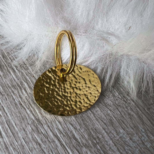 Gold textured pendant on a wooden surface with white fur background