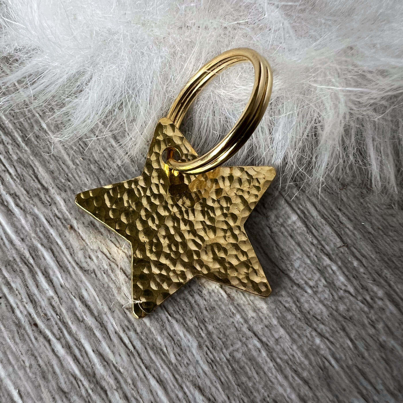 Gold star-shaped hammered tag on a textured surface with white fur background