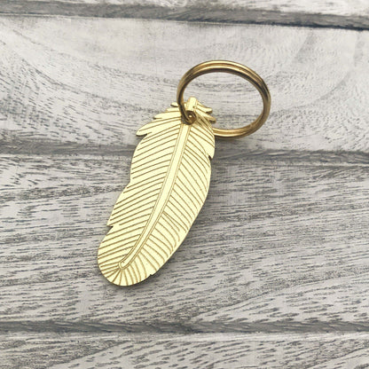Brass feather keychain on a wooden surface