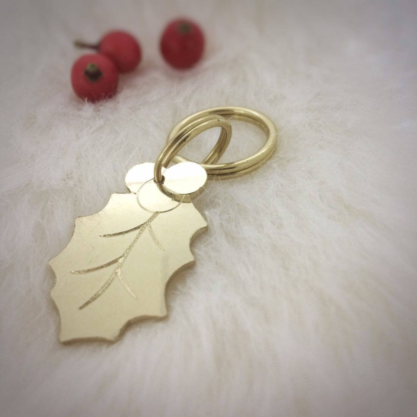 Brass dog tag with holly leaf design on a light background