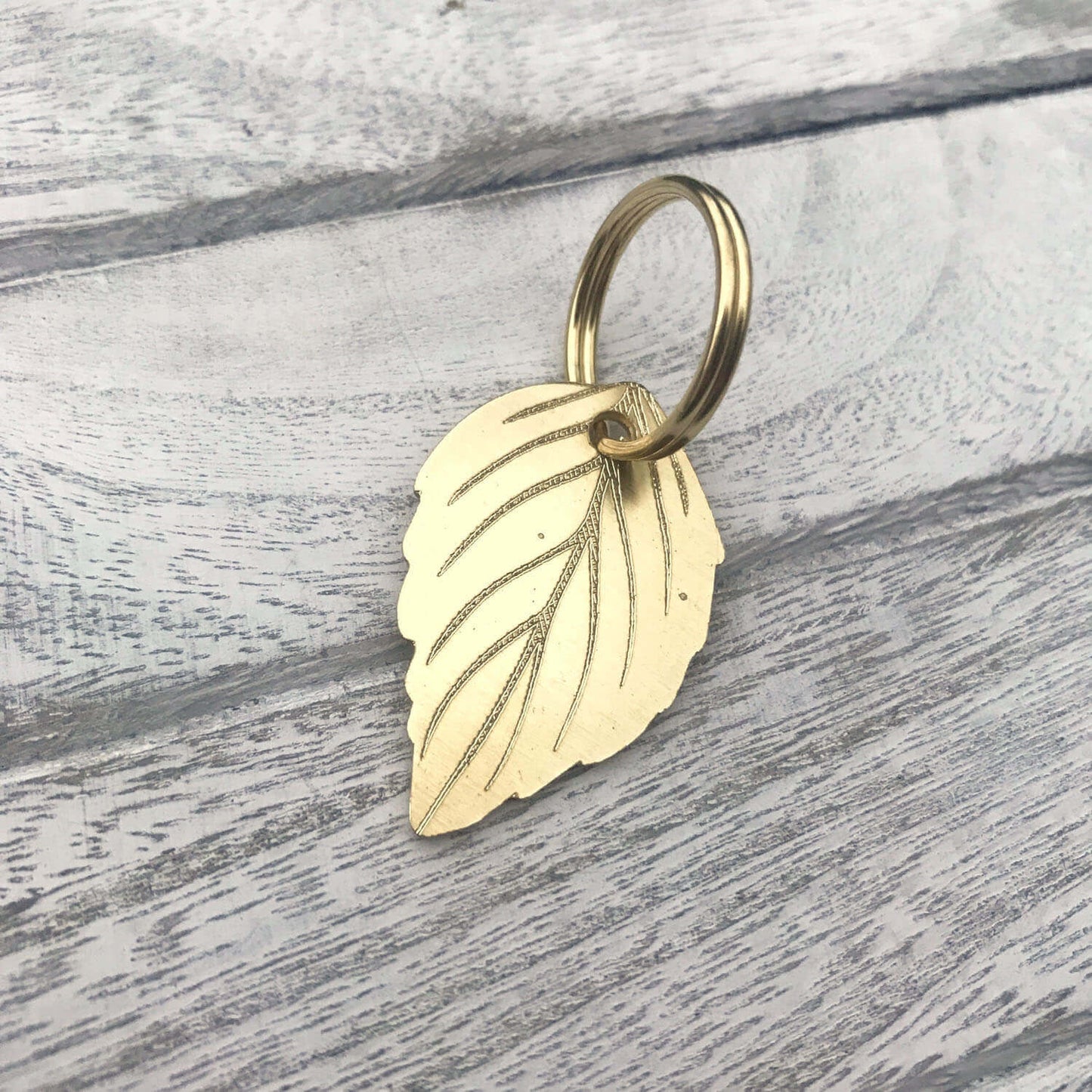 Gold leaf-shaped keychain on a wooden surface