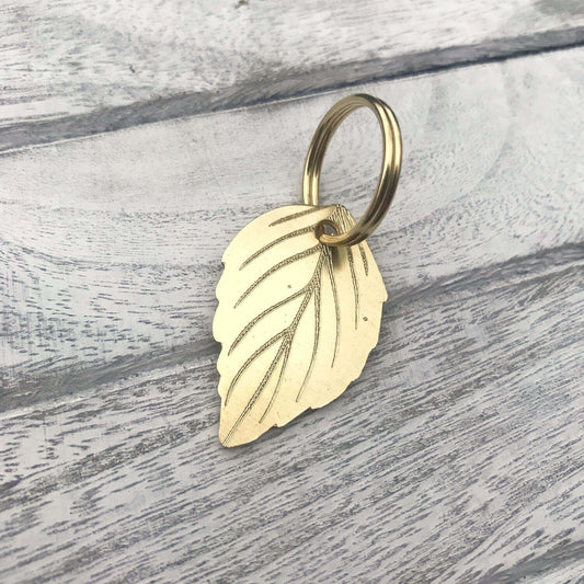 Gold leaf-shaped keychain on a wooden surface