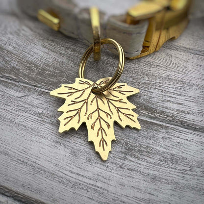 Gold leaf-shaped dog ID tag on a wooden surface