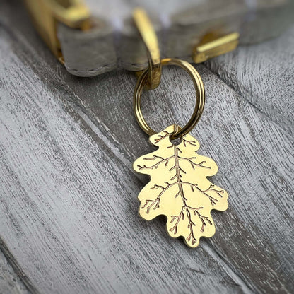 Gold leaf-shaped dog ID tag on a wooden surface