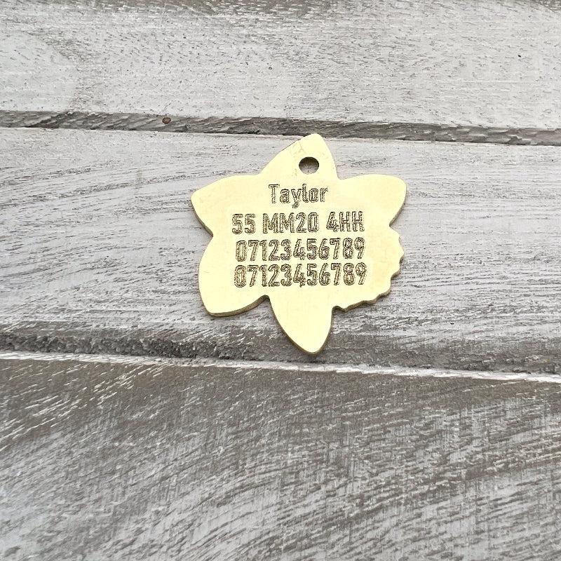 Brass Flower Shaoe with Engraved Text on Wood Background
