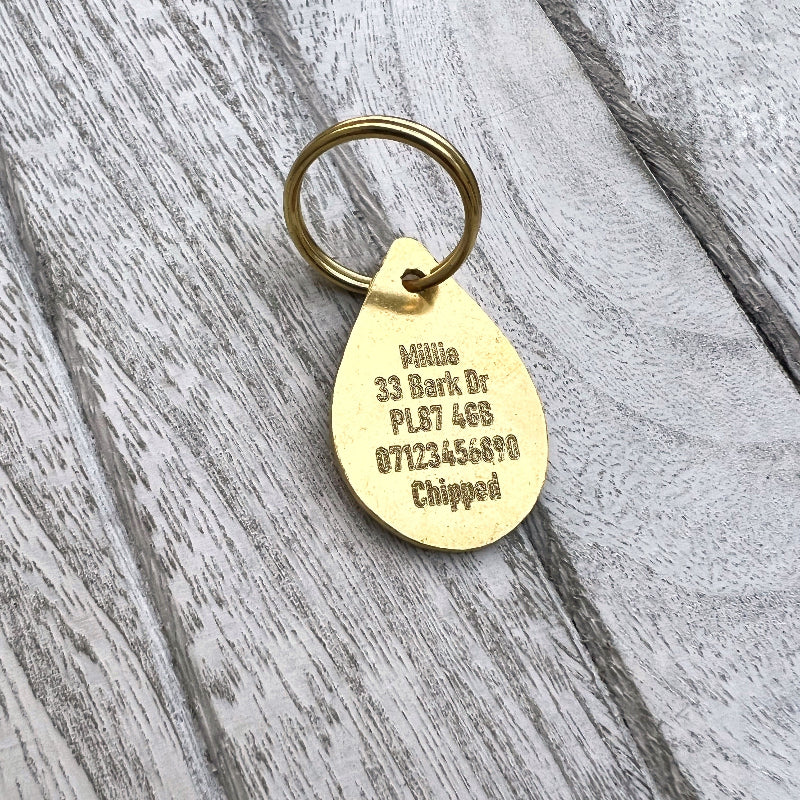 Brass Teardrop With Text and Wood Background