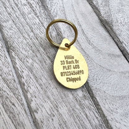 Brass Teardrop With Text and Wood Background